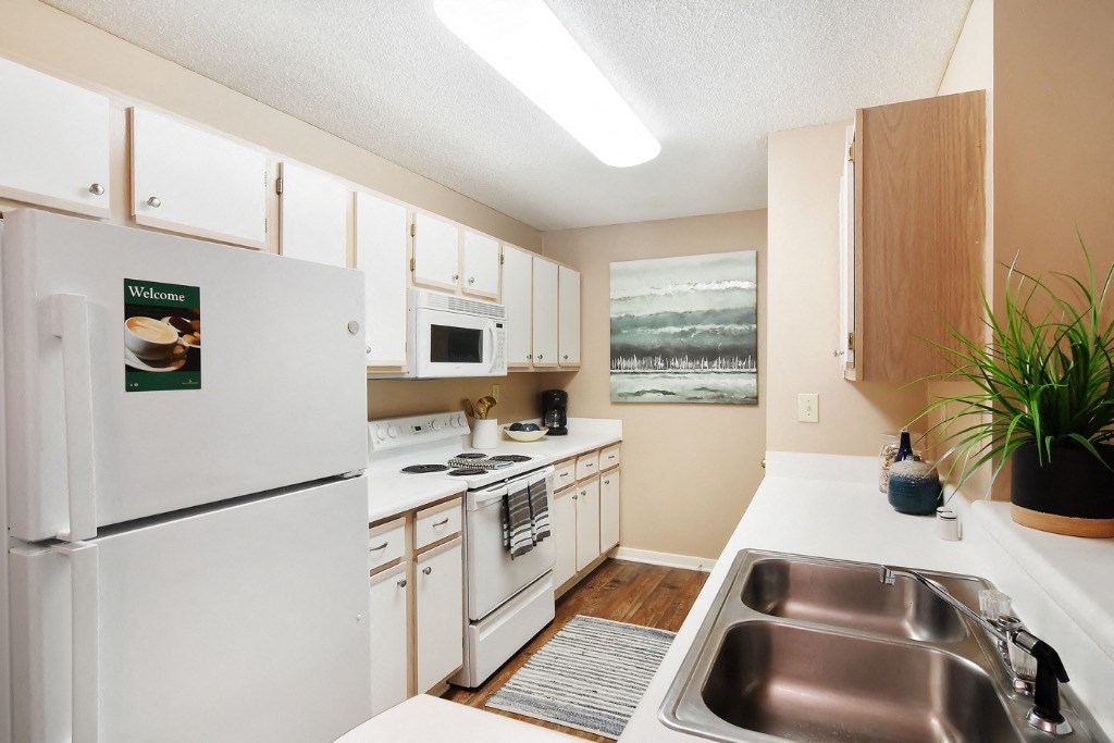 a kitchen with white appliances and wooden cabinets at Lexington Pointe Apartment Homes, Oxford, Mississippi