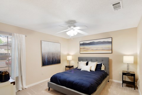 the master bedroom has a large bed and a ceiling fan at Lexington Pointe Apartment Homes in MS 38655