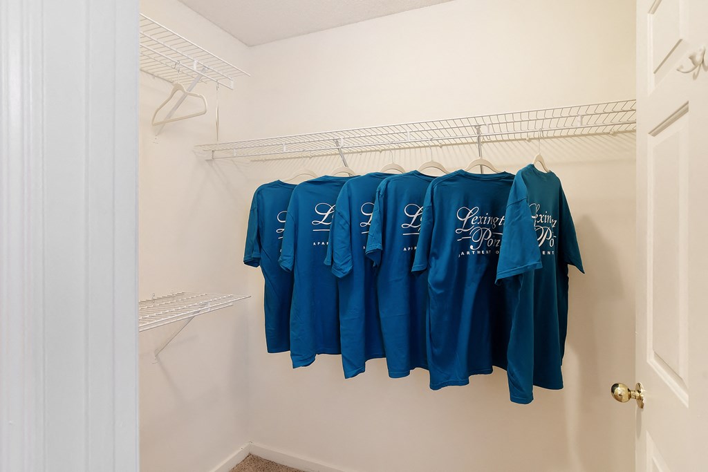 a walk in closet with shirts hanging on a rack at Lexington Pointe Apartment Homes in Oxford, MS 