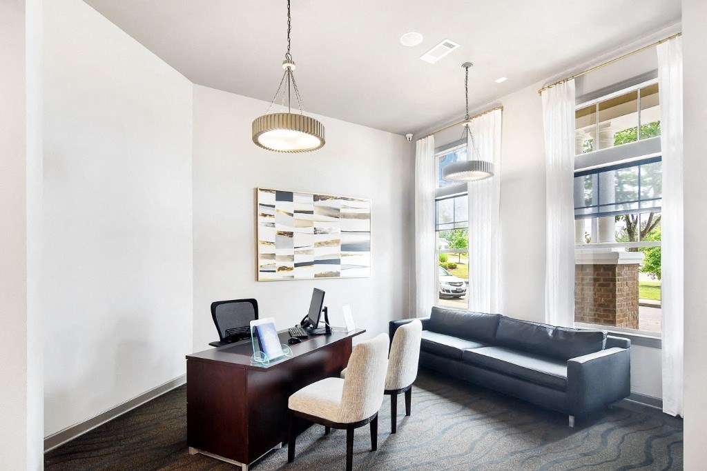 a room with a desk and chairs and a couch in front of a window at Faulkner Flats Apartment Homes, Oxford, Mississippi