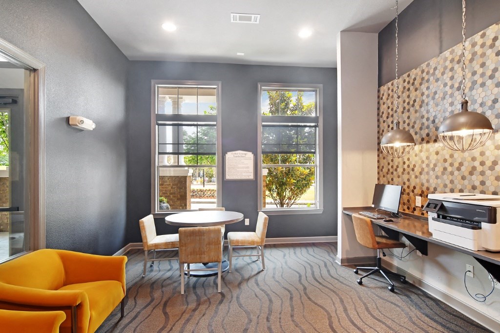 a room with a table and chairs and a computer on a desk at Faulkner Flats Apartment Homes, Oxford, Mississippi