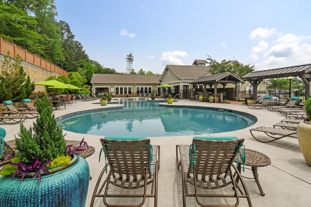 a swimming pool with lounge chairs and umbrellas at Faulkner Flats Apartment Homes, Oxford, MS