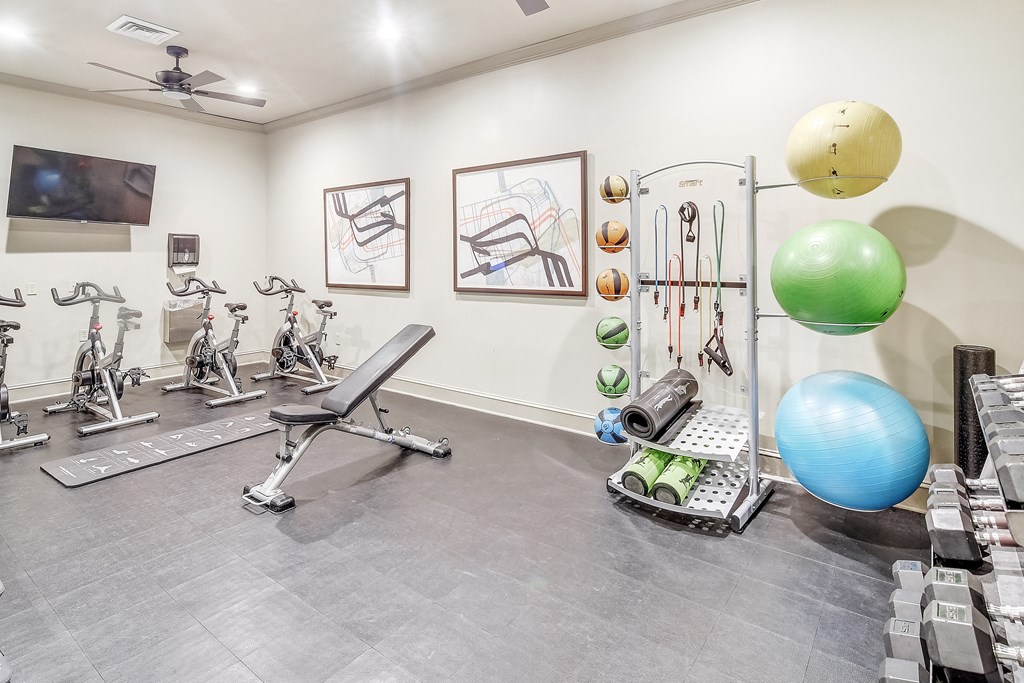 a home gym with exercise equipment and paintings on the wall at Cambridge Station Apartment Homes, Oxford, MS, 38655