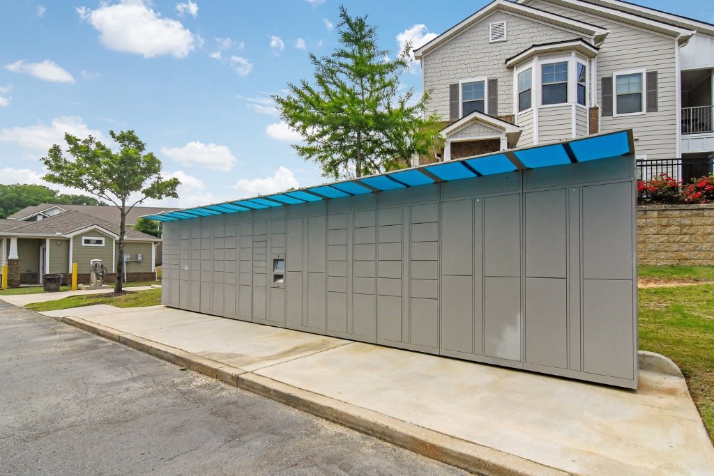 a detached garage with a blue roof and a gray house in the background at Faulkner Flats Apartment Homes, Oxford, Mississippi