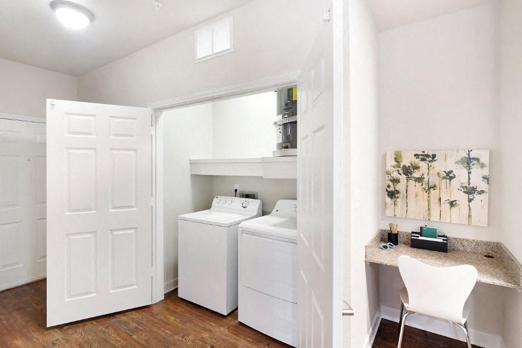 a room with a washer and dryer and a desk with a chair at Faulkner Flats Apartment Homes, Oxford, MS