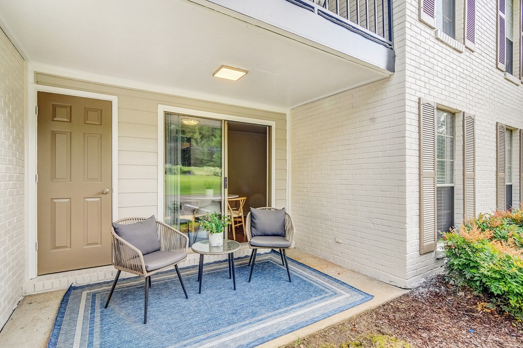 a patio with two chairs and a table on a blue rug at Cambridge Station Apartment Homes, Mississippi