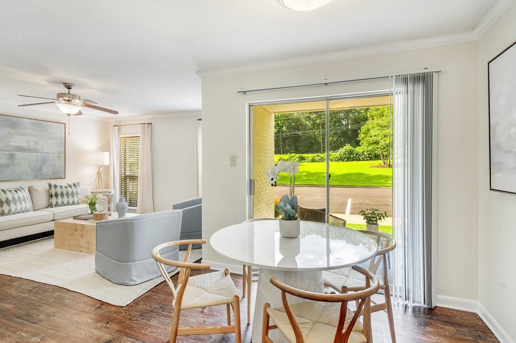 a living room with a round table and a sliding glass door at Cambridge Station Apartment Homes, Oxford, MS, 38655