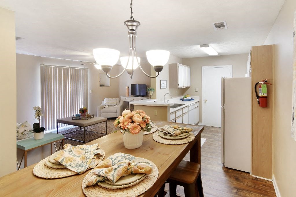 a dining area with a table and chairs and a kitchen in the background  at Parklane Apartment Homes, Mississippi