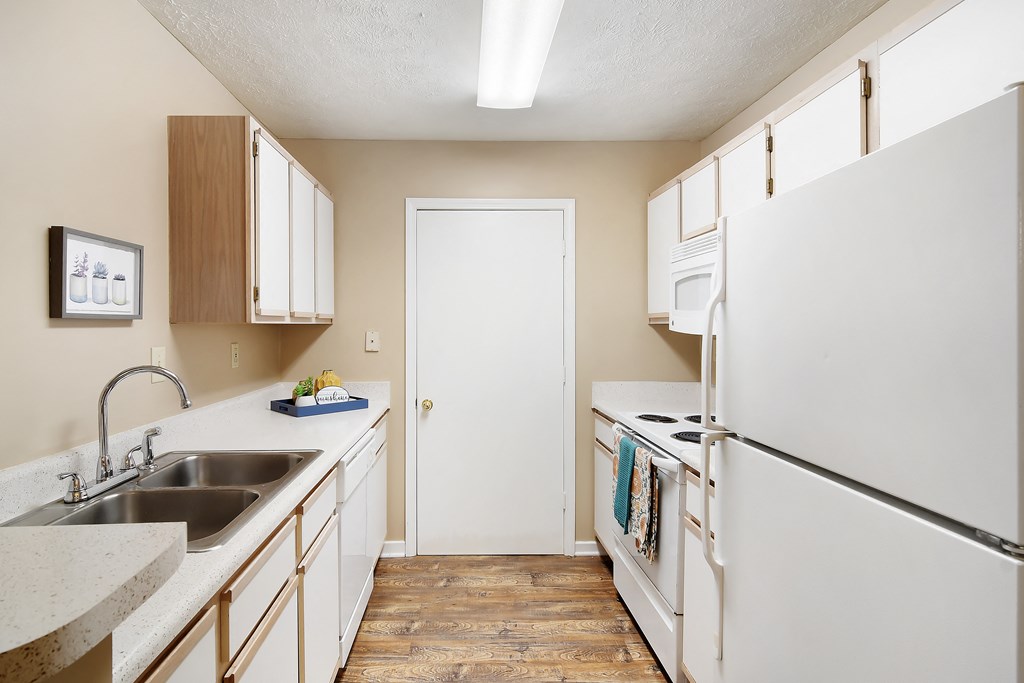 an empty kitchen with white appliances and counters and a white refrigerator at Parklane Apartment Homes, McComb