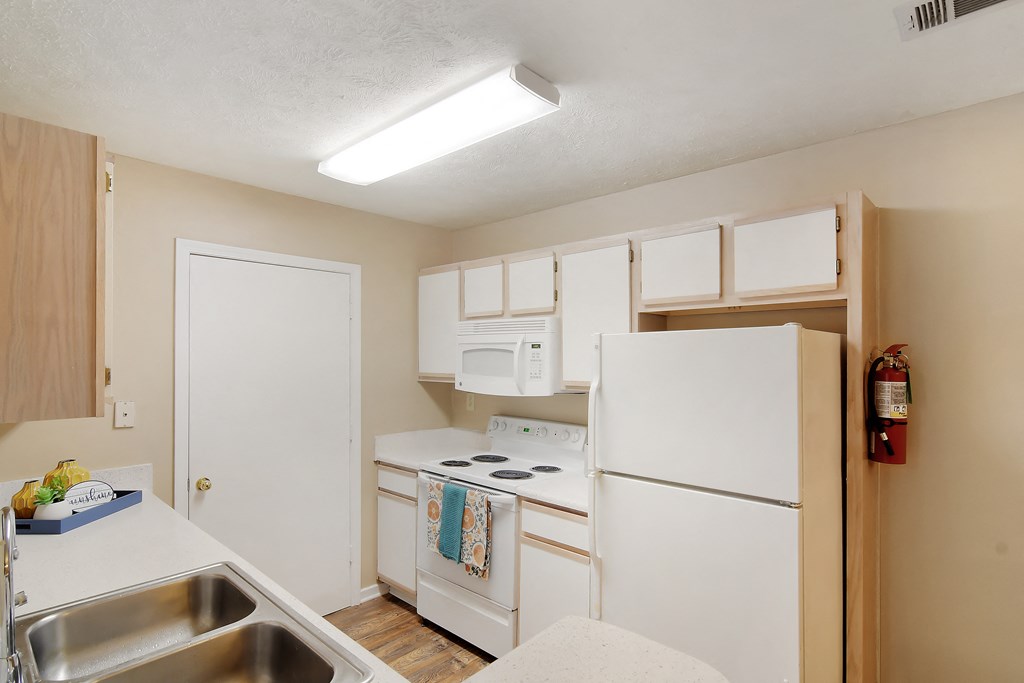 a kitchen with white appliances and a sink and a refrigerator  at Parklane Apartment Homes, McComb, Mississippi