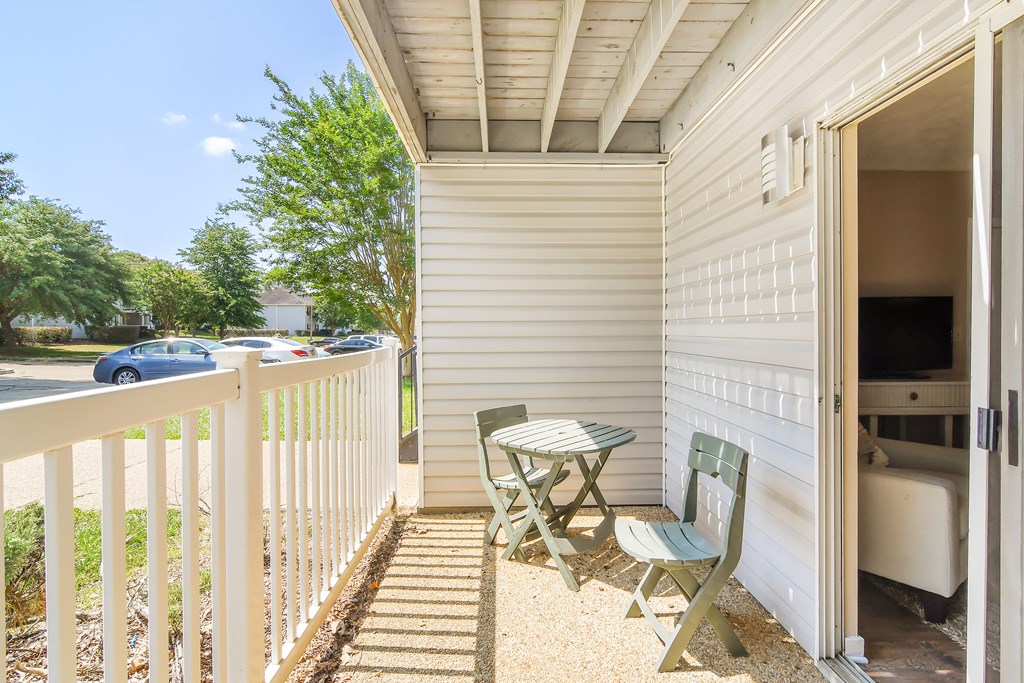 a balcony with a table and two chairs and a parking lot at Parklane Apartment Homes, McComb