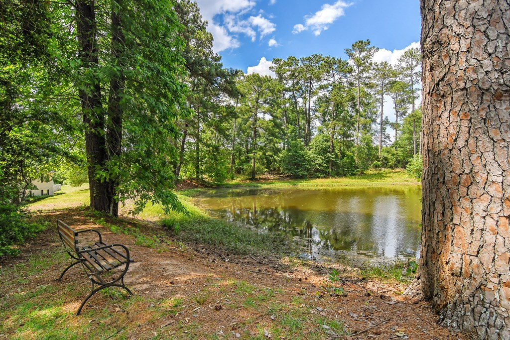 a bench sitting next to a pond at Parklane Apartment Homes, McComb
