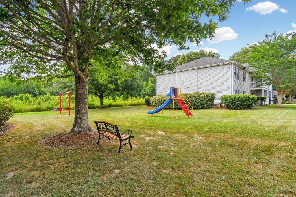 a park with a swing set and a bench in front of a tree  at Parklane Apartment Homes, Mississippi, 39648