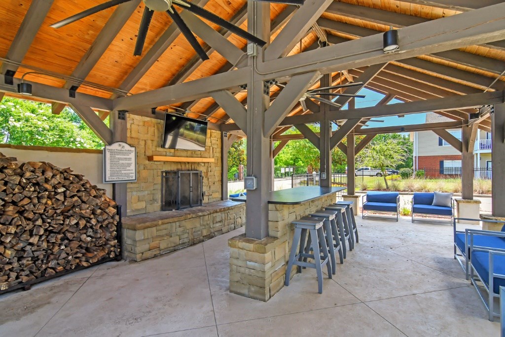 a covered patio with a fireplace and a bar with stools at Landing at Willow Bayou Apartment Homes, Bossier City, Louisiana