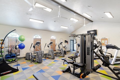 a gym with cardio equipment and weights on the floor