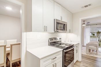 A kitchen with white cabinets and a stove top oven and microwave at The Oliver Apartment Homes in Olive Branch, MS 38654