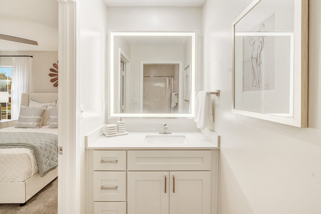 a white bathroom with a sink and a mirror at The Oliver Apartment Homes in Olive Branch, MS