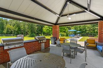 a covered patio with a barbecue and tables and chairs