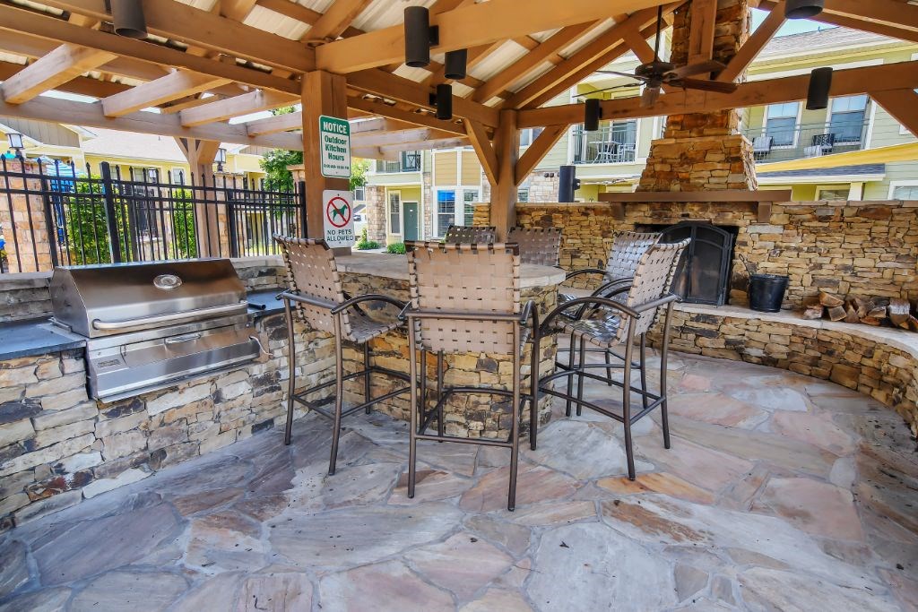 a patio with a grill and a table and chairs  at Wellington Grande Apartment Homes, Longview, 75605