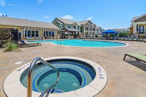 community pool and hot tub with apartment buildings in the background  at Wellington Grande Apartment Homes, Longview, TX