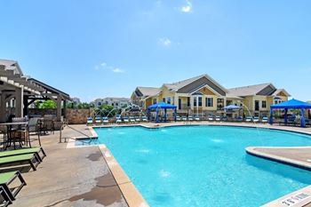 the preserve at ballantyne commons community swimming pool with lounge chairs and umbrellas at Wellington Grande Apartment Homes, Longview, Texas
