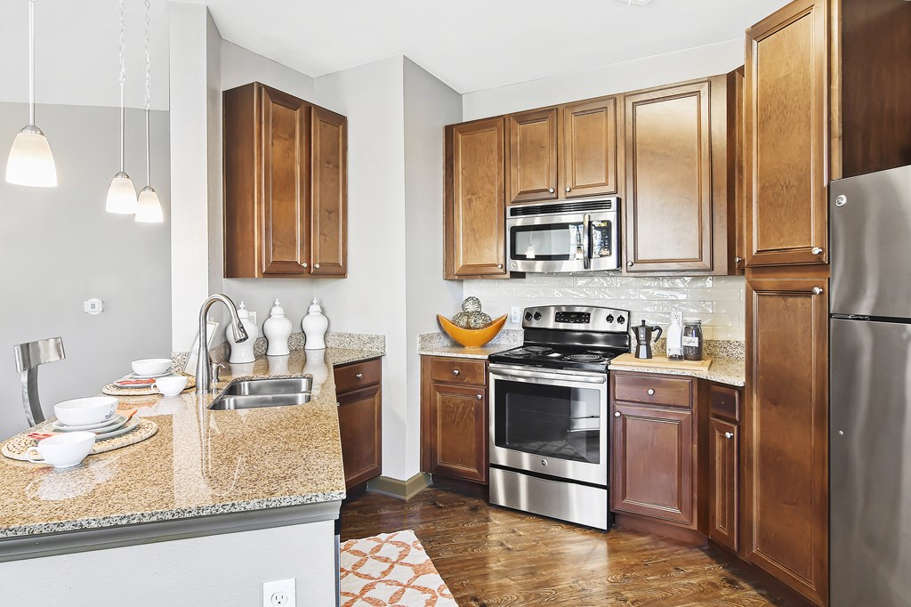 a kitchen with stainless steel appliances and granite counter tops at Wellington Grande Apartment Homes, Texas