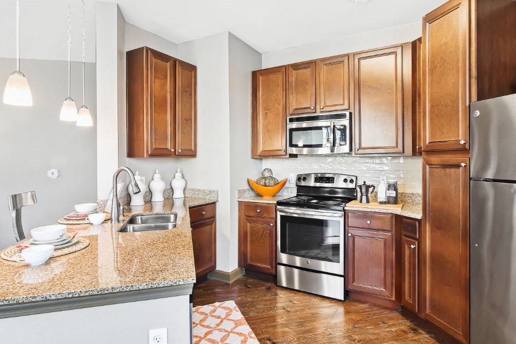 a kitchen with wooden cabinets and stainless steel appliances  at Wellington Grande Apartment Homes, Longview, TX, 75605