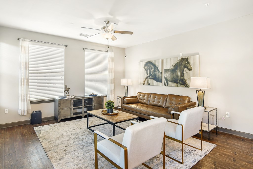 a living room with a leather couch and two white chairs at Wellington Grande Apartment Homes, Longview, TX, Texas