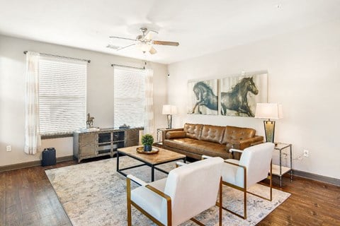 a living room with a leather couch and two white chairs  at Wellington Grande Apartment Homes, Texas, 75605