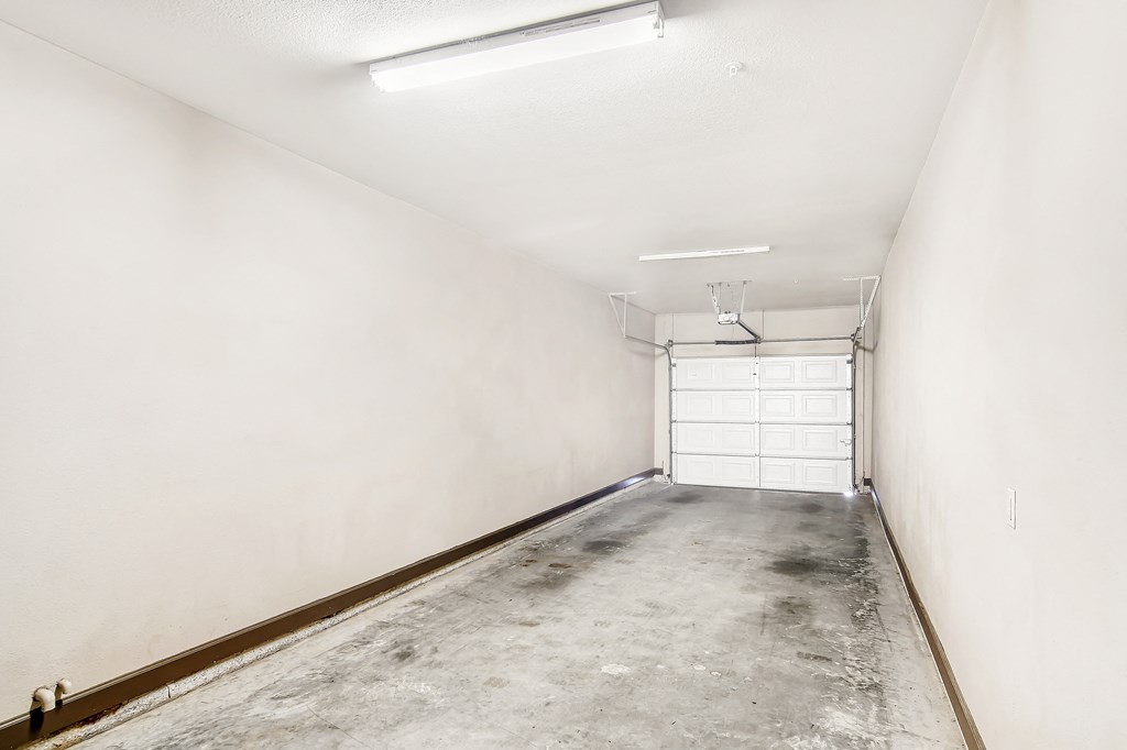 an empty garage with a white wall and a garage door at Wellington Grande Apartment Homes, Longview, TX, Texas