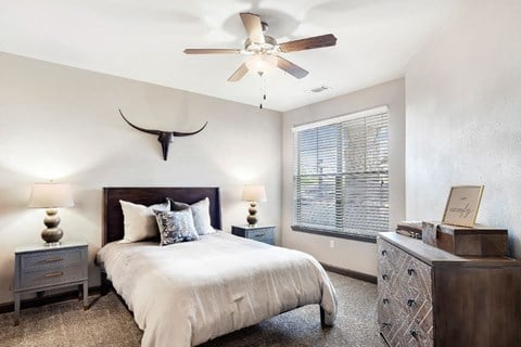 a bedroom with a large bed and a ceiling fan  at Wellington Grande Apartment Homes, Longview, 75605