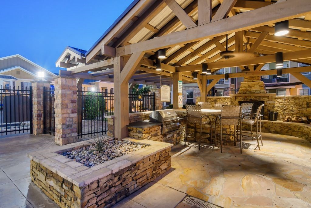 a patio with a grill and a table and chairs  at Wellington Grande Apartment Homes, Longview, TX