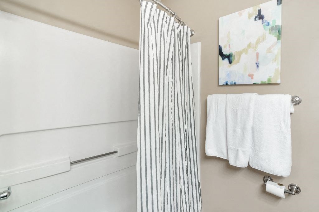 a bathroom with a striped shower curtain and white towels  at Reserve at Gulf Hills Apartment Homes, Mississippi, 39564