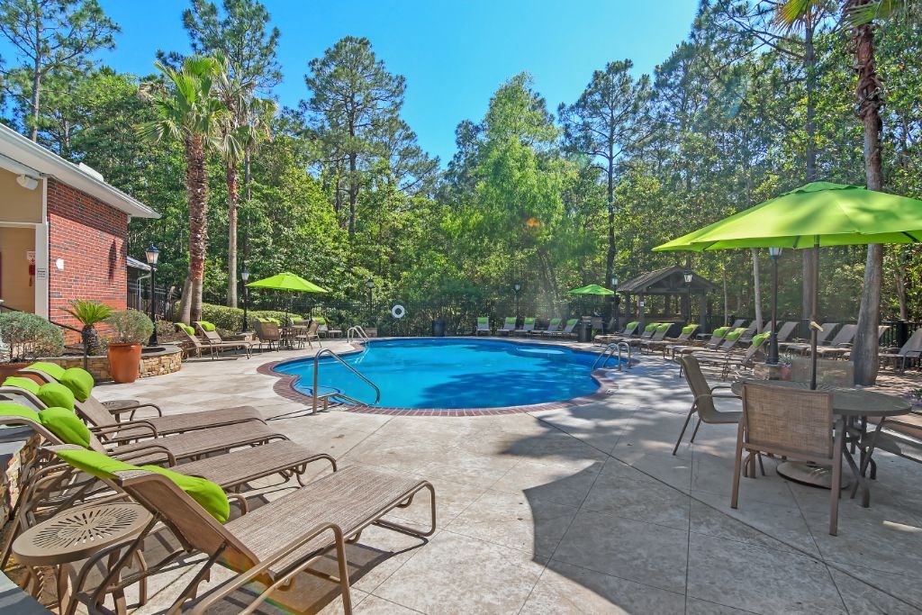a swimming pool with lounge chairs and umbrellas  at Lagniappe of Biloxi Apartment Homes, Biloxi, 39532