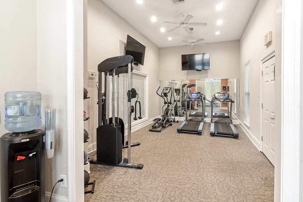 a home gym with cardio equipment and a television at Lagniappe of Biloxi Apartment Homes, Biloxi