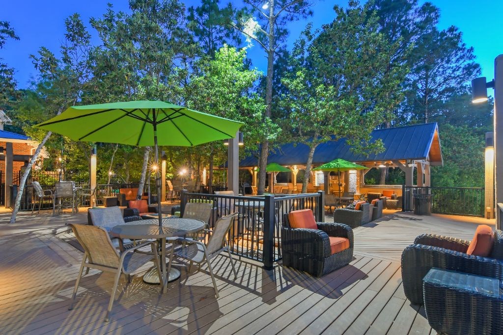 a large deck with tables and chairs and umbrellas  at Lagniappe of Biloxi Apartment Homes, Mississippi