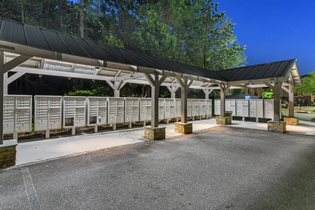 a covered area with white benches and trees in the background  at Lagniappe of Biloxi Apartment Homes, Mississippi
