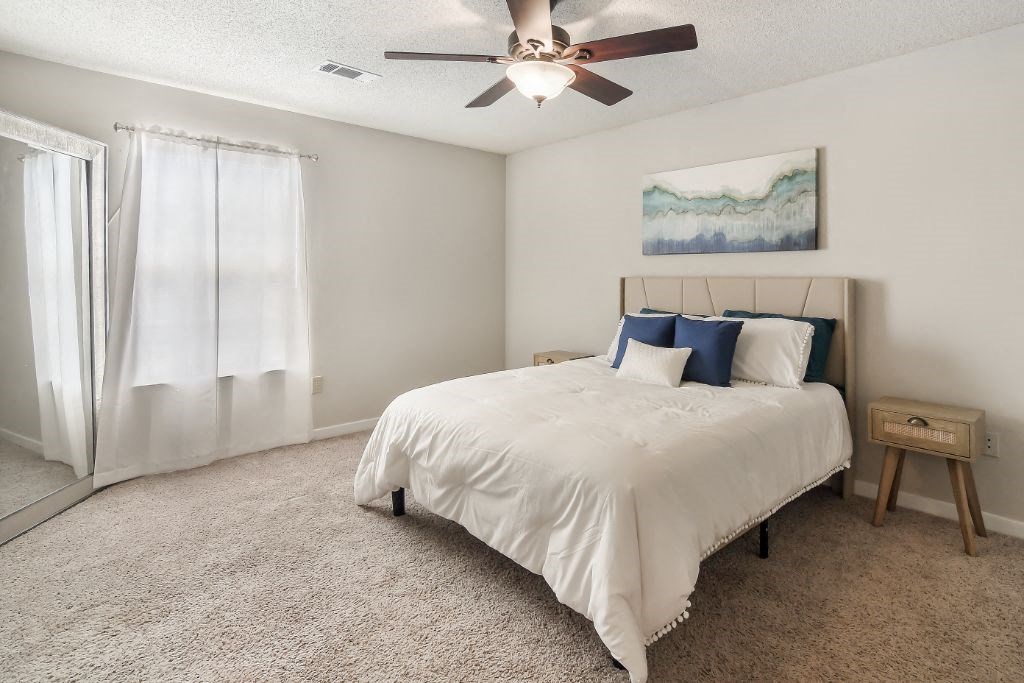 a bedroom with a bed and a ceiling fan  at The Pointe Apartment Homes, Gautier, 39553