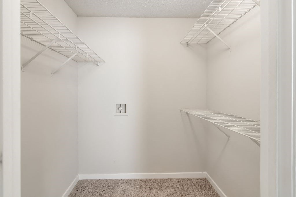 a bedroom with white walls and a white closet with white shelves  at The Pointe Apartment Homes, Gautier, MS, 39553