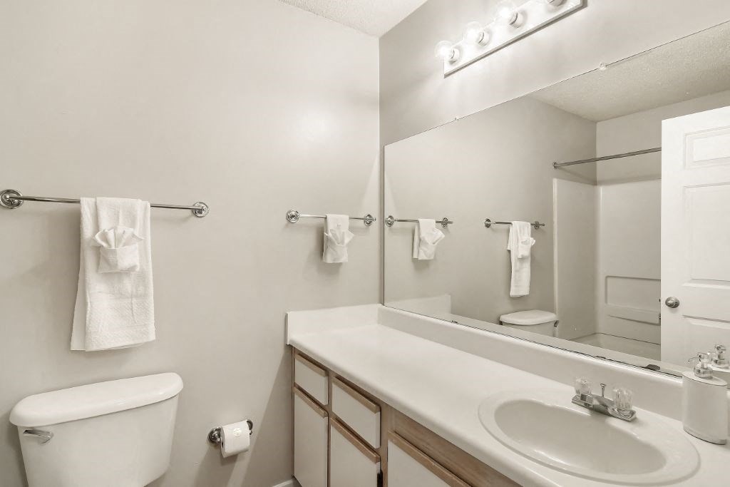 a bathroom with a sink toilet and mirror  at The Pointe Apartment Homes, Gautier, Mississippi