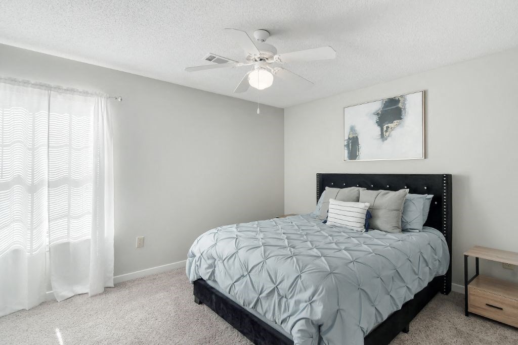 a bedroom with a bed and a ceiling fan  at The Pointe Apartment Homes, Gautier