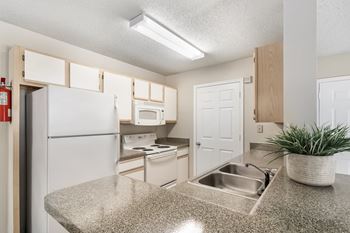a kitchen with white appliances and a granite counter topat The Pointe Apartment Homes, Gautier, Mississippi