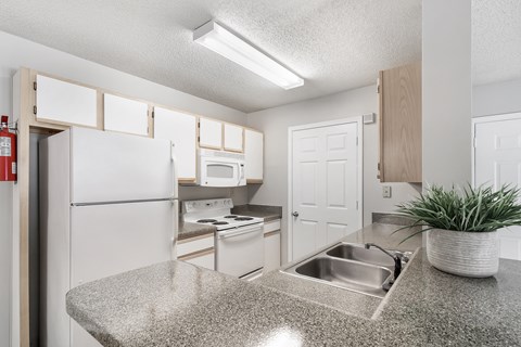 a kitchen with white appliances and a granite counter top at The Pointe Apartment Homes in Gautier, 39553