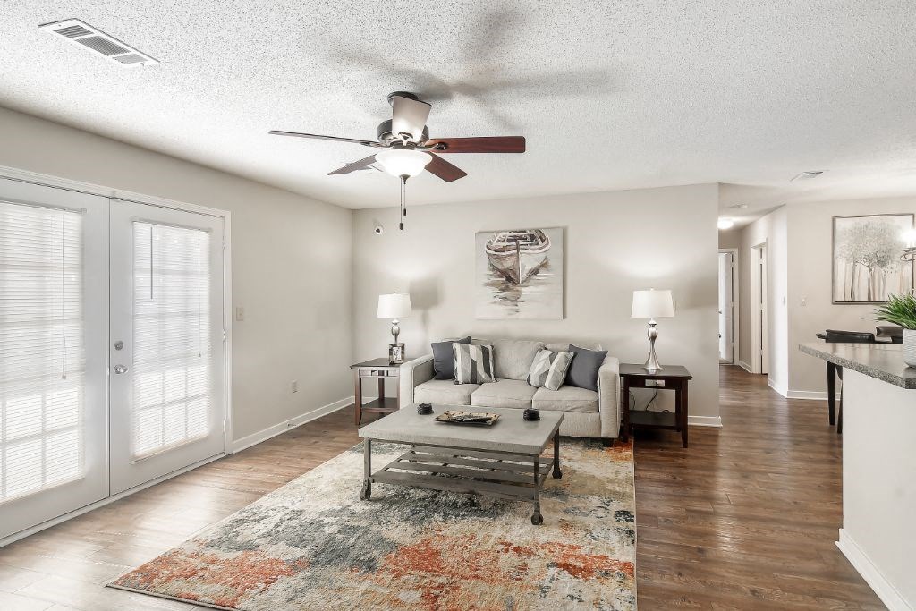 a living room with a couch coffee table and a ceiling fan  at The Pointe Apartment Homes, Gautier, MS