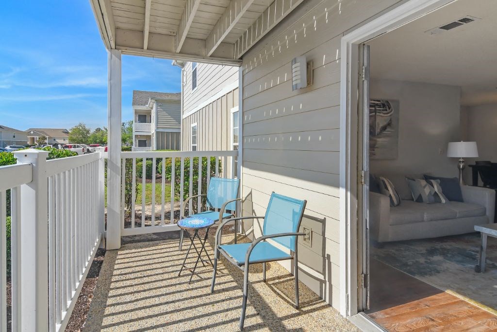 a porch with two blue chairs and a couch in the background  at The Pointe Apartment Homes, Gautier, MS