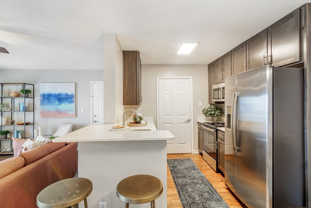 a kitchen and living room with stainless steel appliances and a white counter top at Reserve of Jackson Apartment Homes, Mississippi