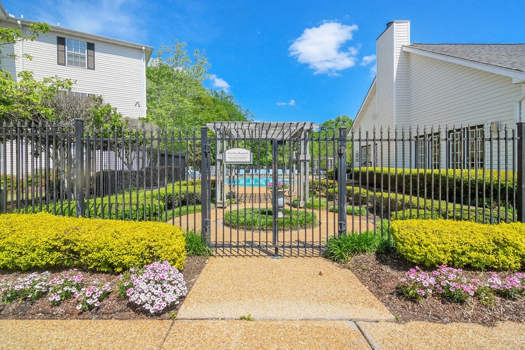 a garden with a pool behind a wrought iron fence at Reserve of Jackson Apartment Homes, Jackson, 39211