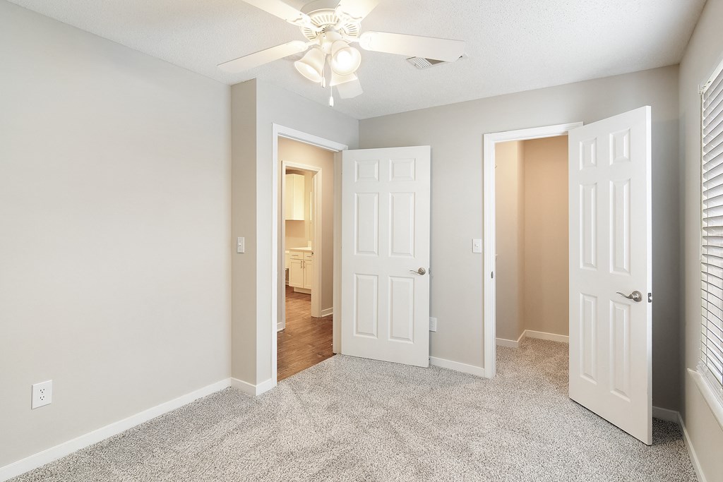 an empty bedroom with white doors and a ceiling fan at The Woodlands Apartment Homes, Meridian, Mississippi
