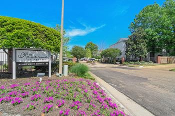 the entrance to a park with purple flowers and a sign at Reserve of Jackson Apartment Homes, Mississippi