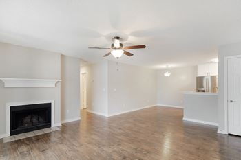 an empty living room with a ceiling fan and a fireplace at The Woodlands Apartment Homes, Meridian, MS